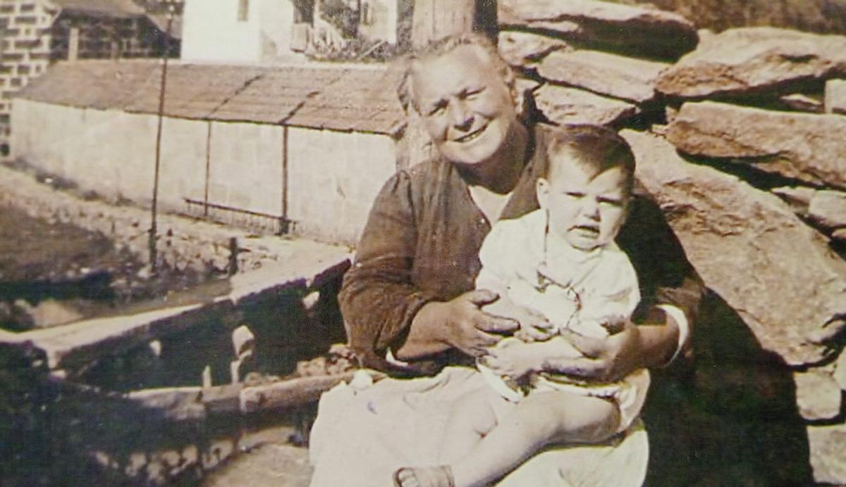 Dolores Buceta, con uno de sus nietos frente al lavadero de O Pailán, a unos metros de su casa familiar.