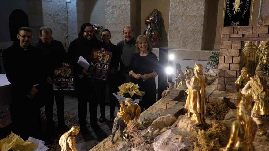 Representes de la cofradía y la parroquia observan algunas de las figuras del belén instalado.