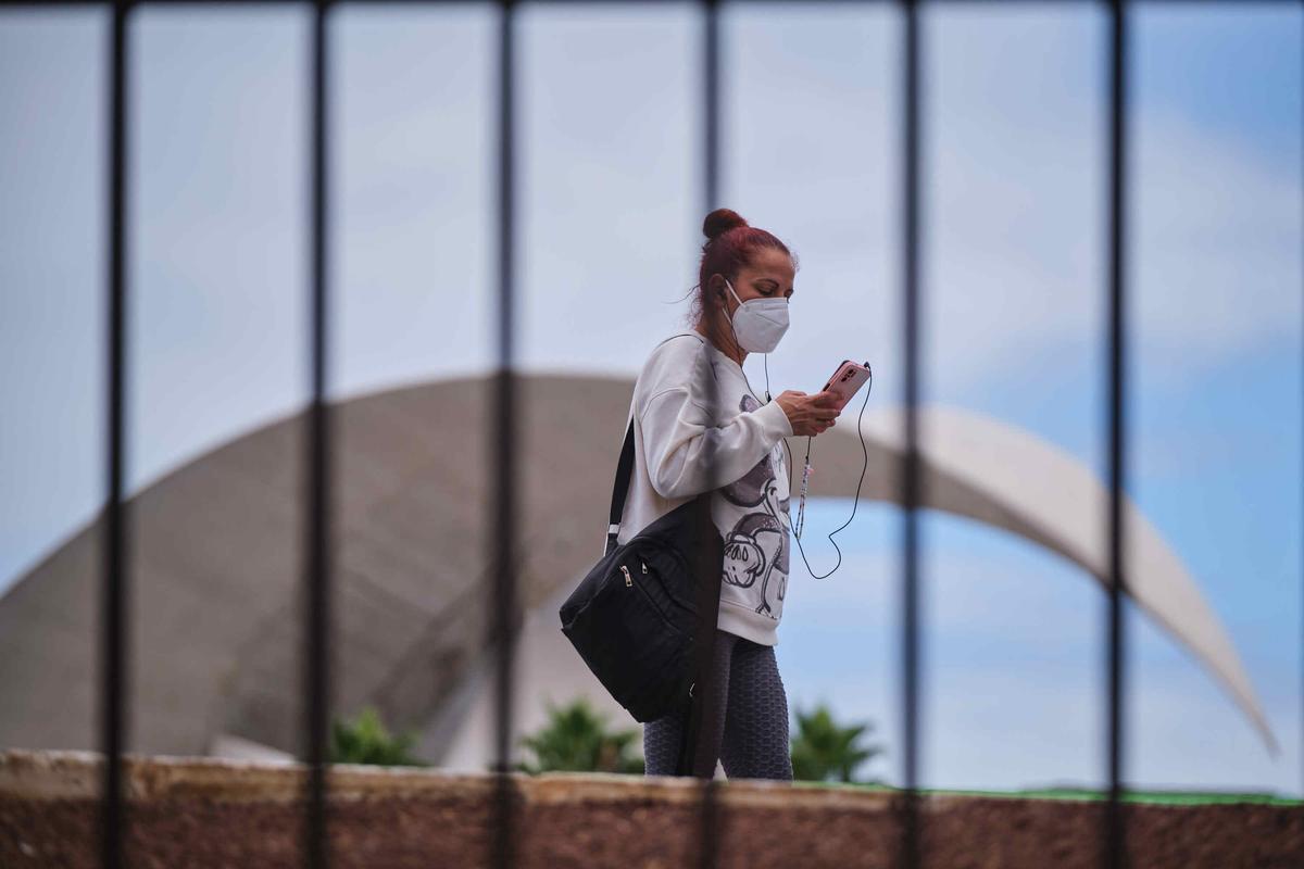 Una mujer pasa por delante del Auditorio Adán Martín (Tenerife) con su mascarilla puesta.
