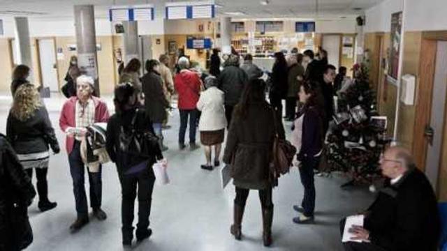 Los pacientes del centro de salud de San Blas hacen cola para ser atendidos en el mostrador de las citas médicas.