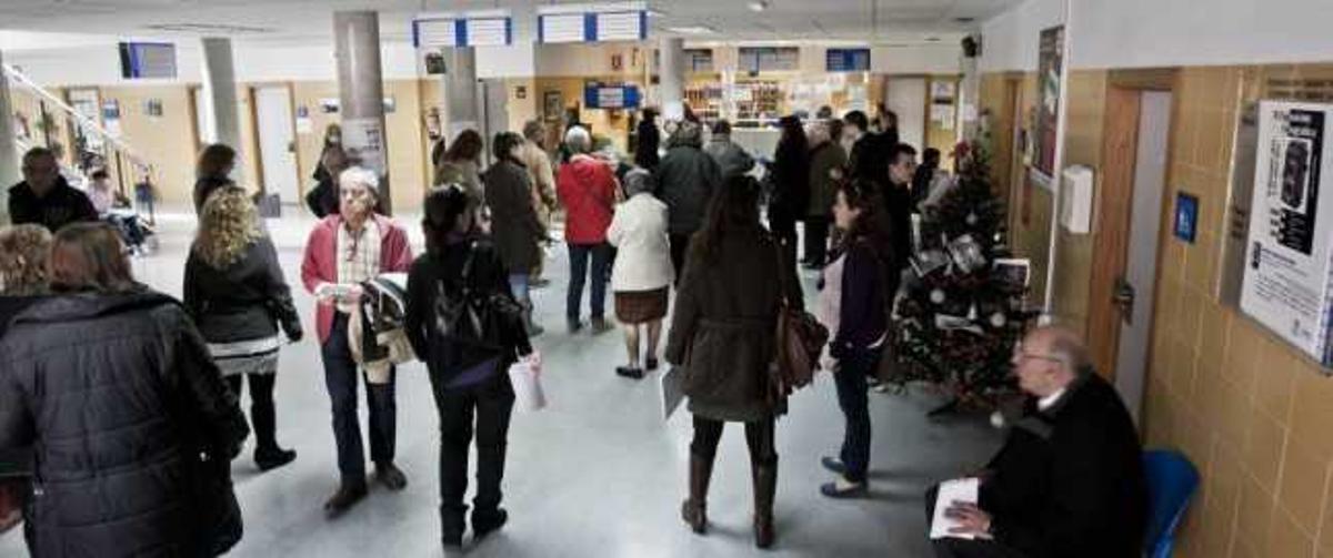 Los pacientes del centro de salud de San Blas hacen cola para ser atendidos en el mostrador de las citas médicas.