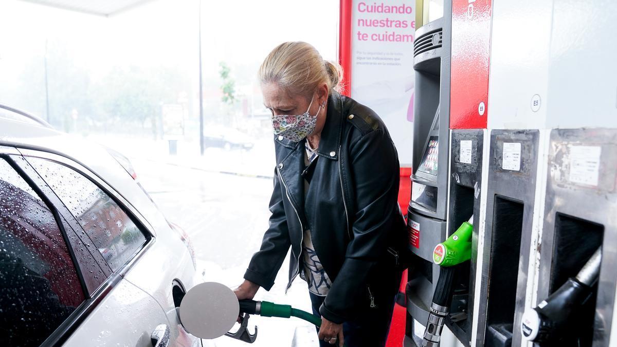 Una mujer pone gasolina a su vehículo en una gasolinera.