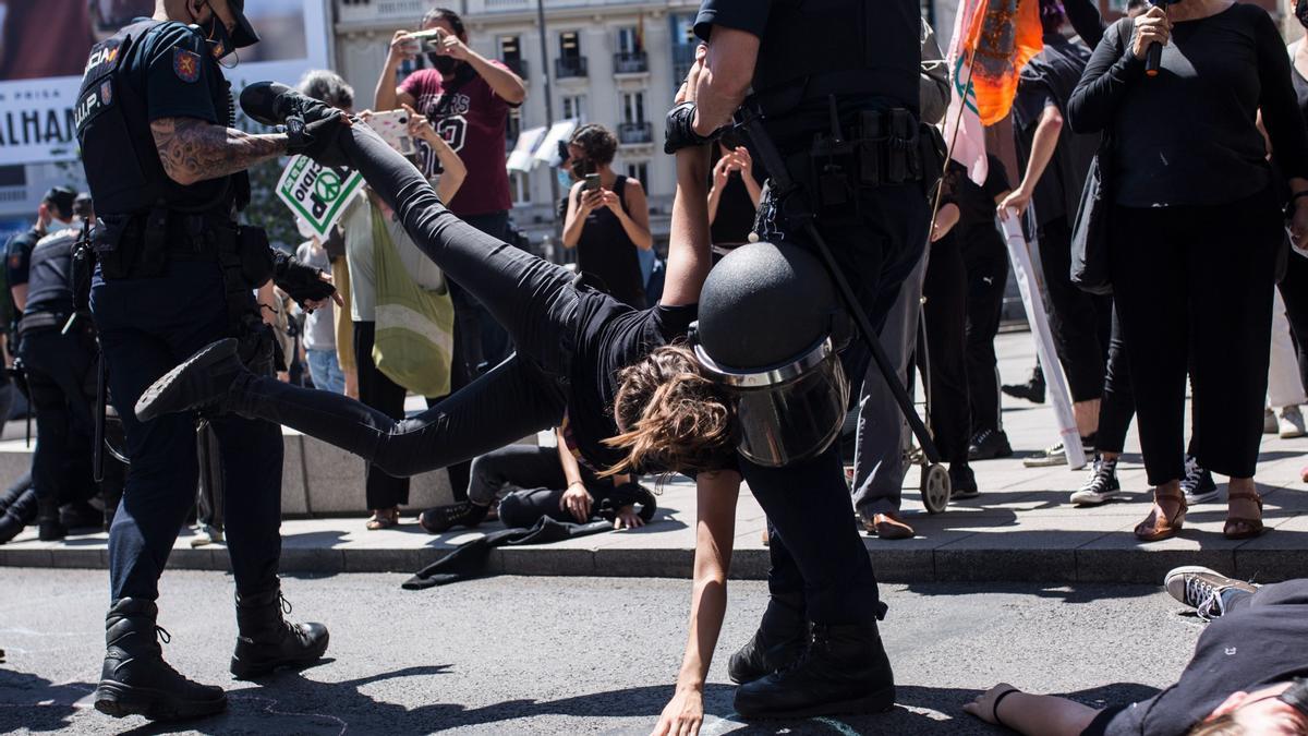 Dos policías nacionales levantan en volandas a una joven durante una manifestación posterior a la entrega del Manifiesto por la criminalización del Ecocidio, este viernes, un día antes del Día Mundial del Medio Ambiente.