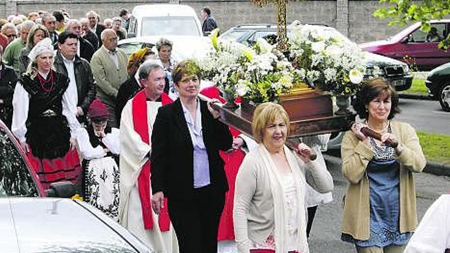 Cuatro mujeres portan la Santa Cruz por los caminos de los alrededores de la iglesia de Jove durante la procesión.