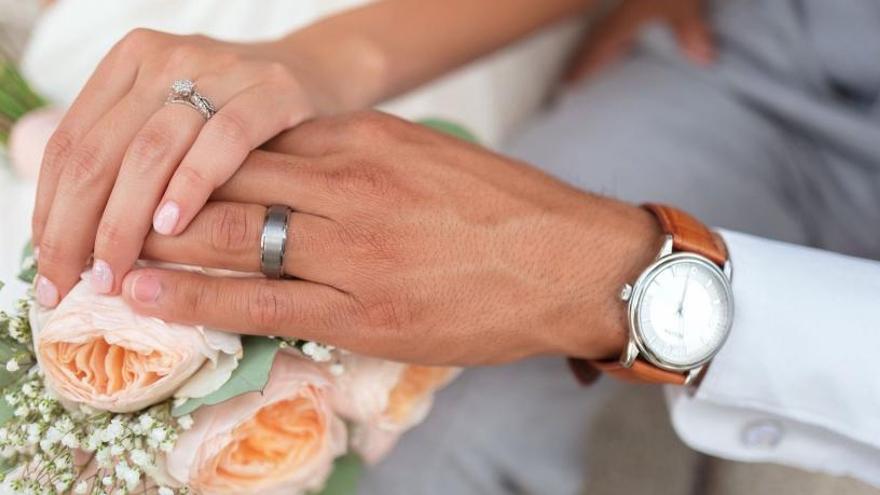 Una pareja se da la mano durante la ceremonia de su boda.