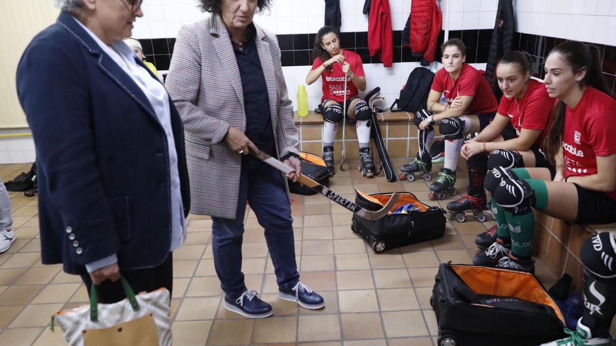 Ana González y Berta Piñán, con un stick en la mano, charlan con las jugadoras del Telecable Gijón. | Marcos León