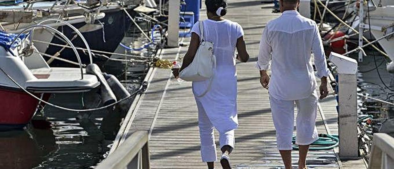 Dos turistas pasean por un pantalán del Muelle Deportivo de Las Palmas de Gran Canaria.