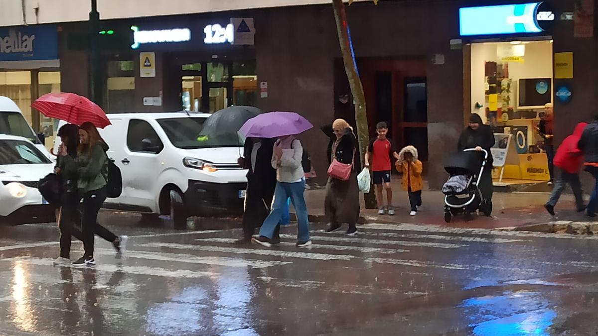 Personas intentando resguardarse de la lluvia en el centro de Alcoy este mediodía.