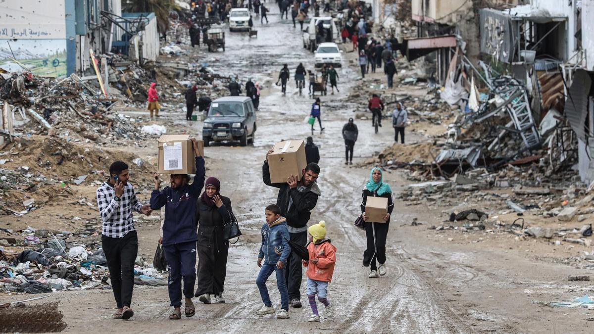 Palestinos con cajas de ayuda humanitaria entregada por la UNRWA en ciudad de Gaza, en medio del alto el fuego entre Israel y Hamás