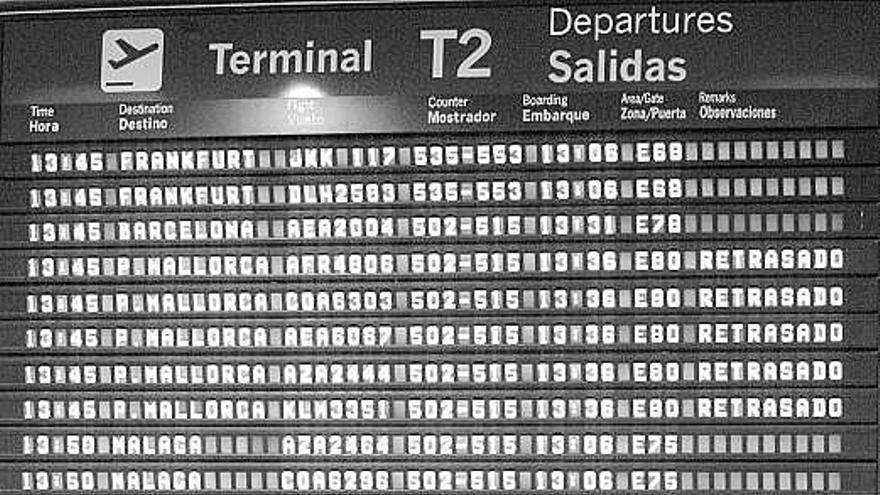 Pasajeros ante un panel informativo de Barajas con vuelos retrasados.