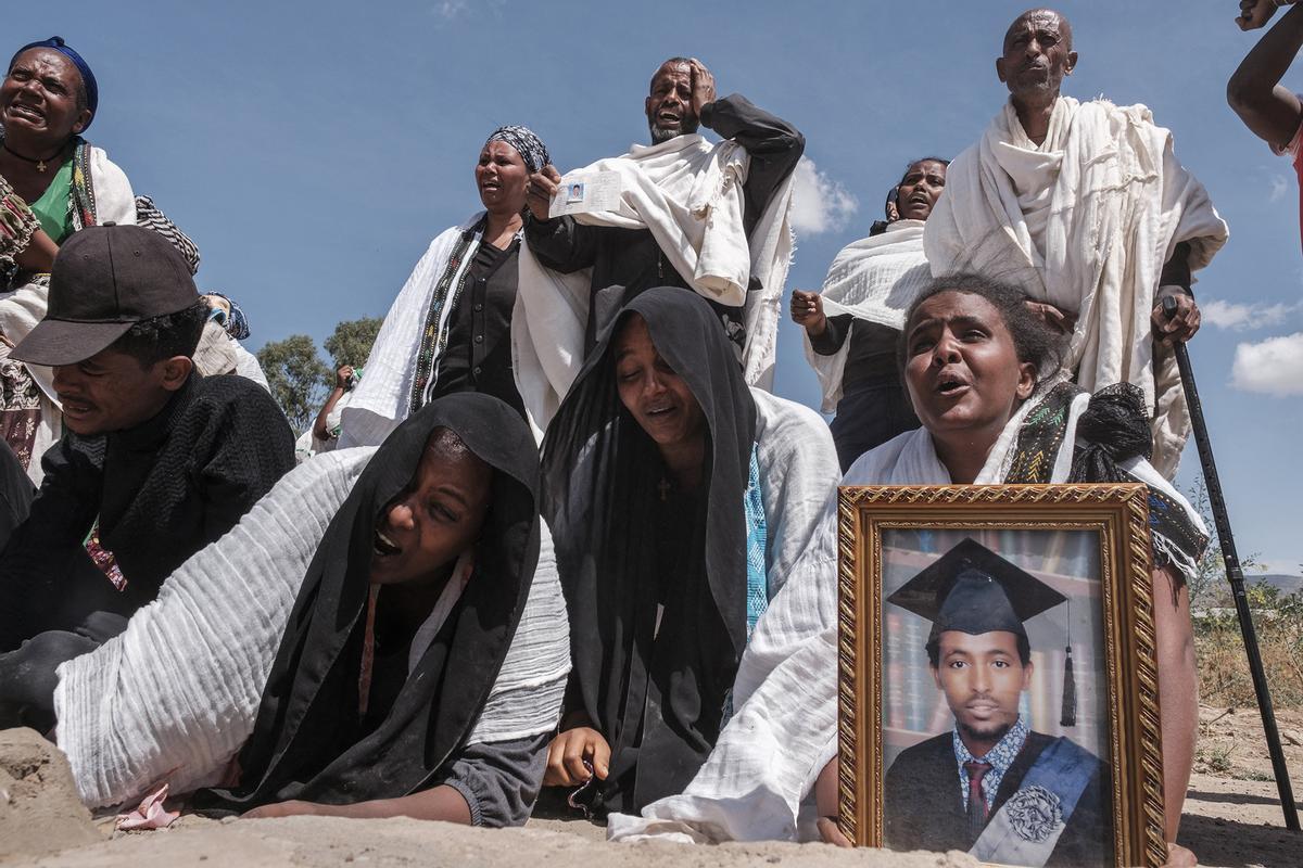 Varias personas lloran frente a la fosa común donde están enterradas 81 víctimas de las tropas eritreas y etíopes. Etiopía, 28 de febrero de 2021.