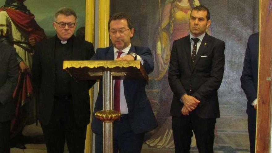 El consejero de Educación, Genaro Alonso, interviniendo durante la presentación de los cuadros restaurados de la monarquía asturiana, entre el alcalde de Cangas, José Manuel González, y el abad de Covadonga, Adolfo Mariño.