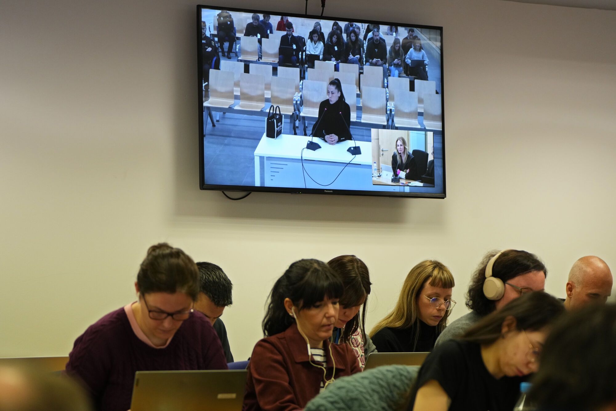 Soccer player Jenni Hermoso testifies, seen on a video screen, as journalists work inside a court on the outskirts of Madrid, Spain, Monday Feb. 3, 2025 during the trial of former president of Spain's soccer federation Luis Rubiales for his unsolicited kiss on Jenni Hermoso. (AP Photo/Manu Fernandez)