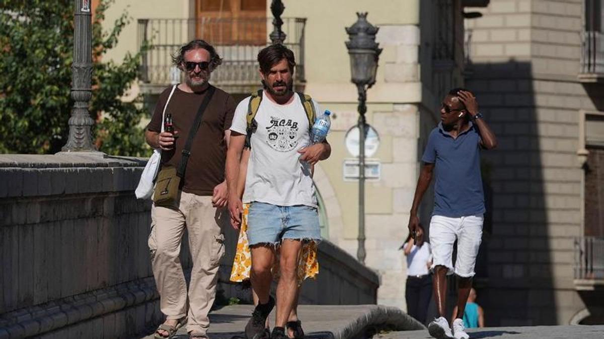 Persones passejant avui per Girona amb ampolles d'aigua per hidratar-se.