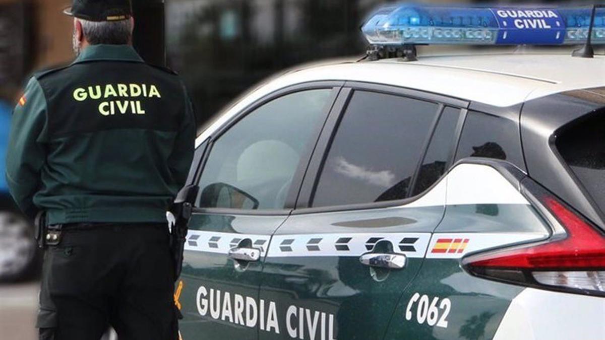 Un agente de la Guardia Civil junto a un vehículo oficial.