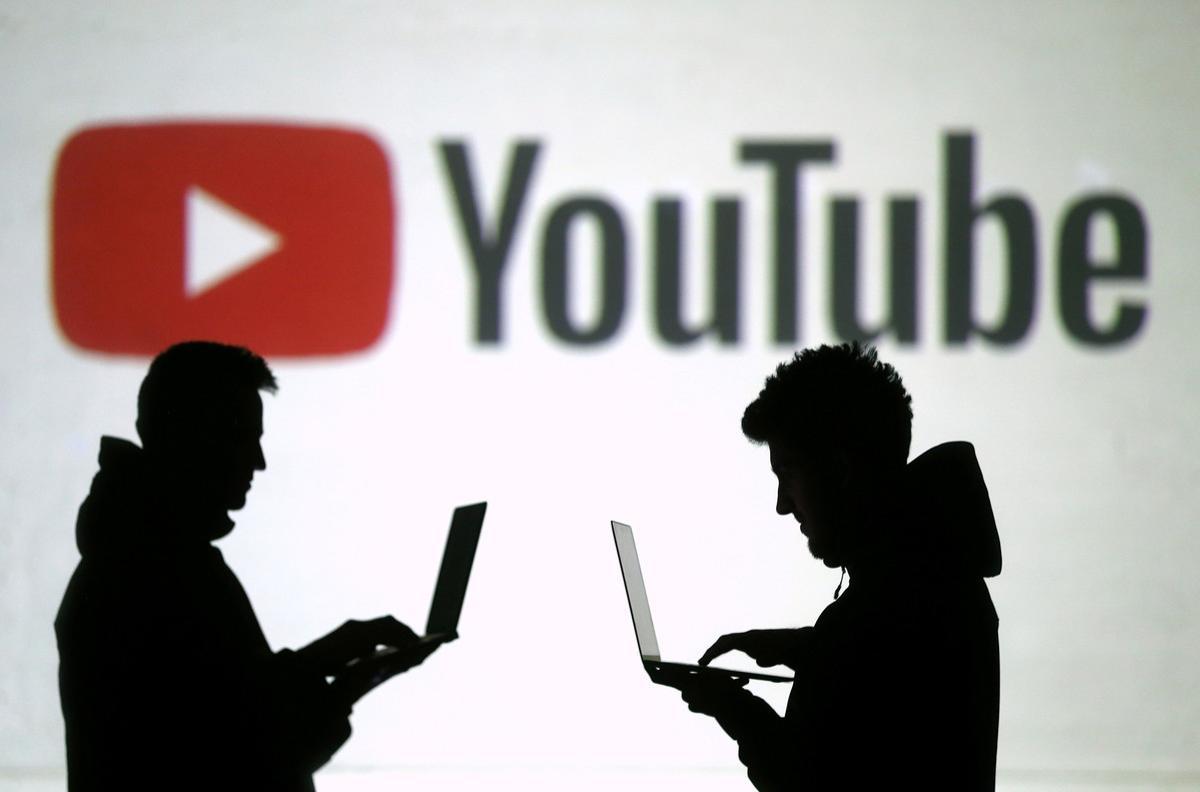 FILE PHOTO:    Silhouettes of mobile device users are seen next to a screen projection of Youtube logo in this picture illustration taken March 28, 2018.  REUTERS/Dado Ruvic/Illustration/File Photo