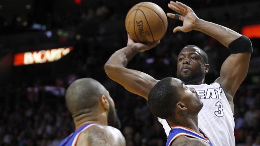 Dwyane Wade de Miami Heat trata de pasar ante dos jugadores de los New York Knicks