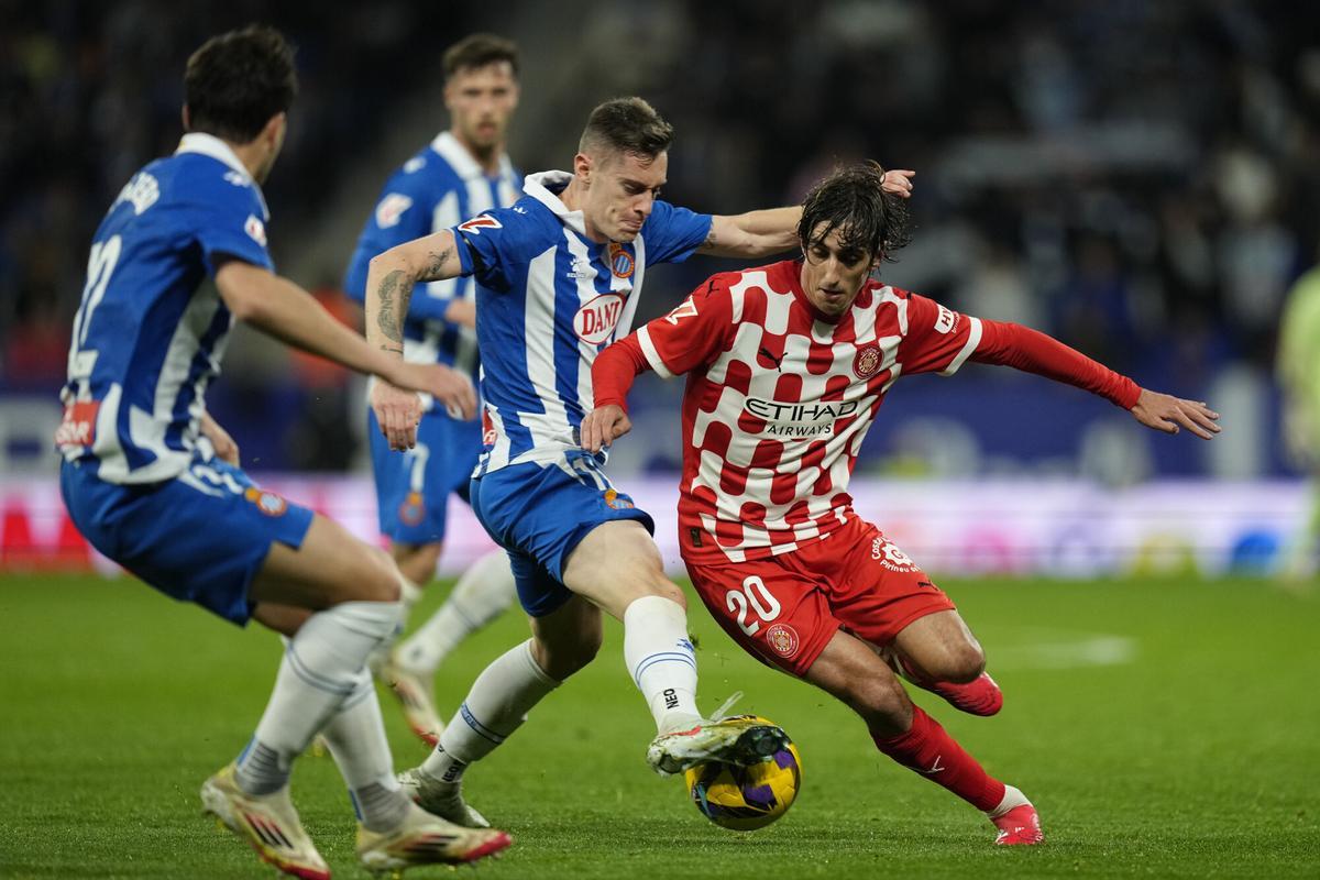 CORNELLÀ DE LLOBREGAT (BARCELONA), 10/03/2025.- El delantero del Girona Bryan Gil (d) lucha con Pol Lozano (c), del Espanyol, durante el partido de la jornada 27 de LaLiga que RCD Espanyol y Girona FC disputan hoy lunes en el RCDE Stadium. EFE/Enric Fontcuberta