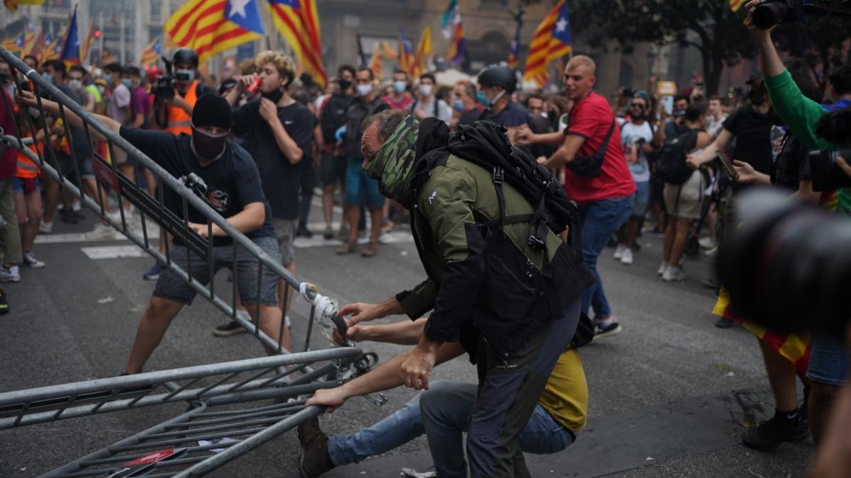 Persones encaputxades retiren les tanques situades davant de la comissaria de la Policia Nacional de Via Laietana de Barcelona