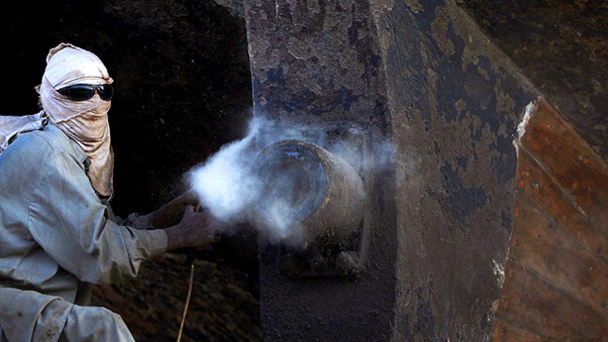 Un treballador fa les tasques de manteniment d’un vaixell de càrrega de fusta a Karachi (Pakistan). Per a la reforma d’un d’aquests vaixells es necessiten 20 obrers durant una setmana.