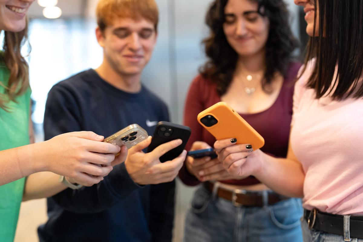 Jóvenes mirando sus teléfonos móviles y hablando