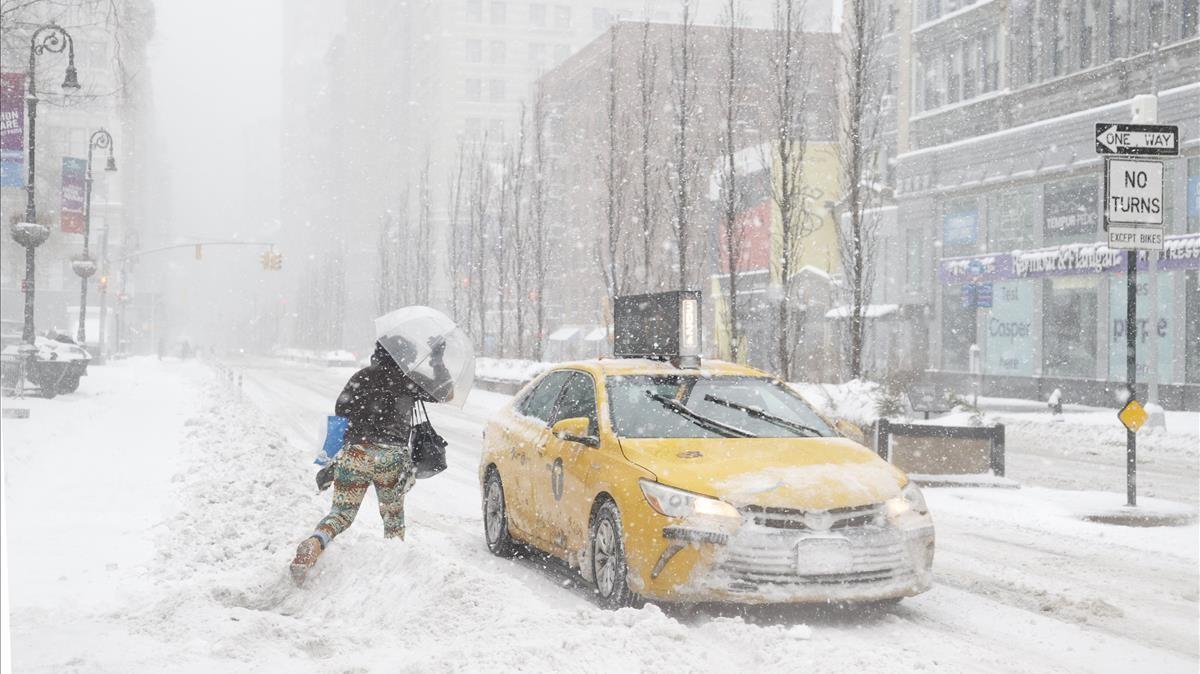 Una mujer corre para coger un taxi en la ciudad de Nueva York nevada