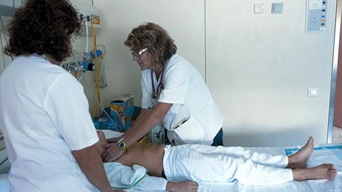 Una médica y una enfermera atienden a un paciente en el Vall d'Hebron.