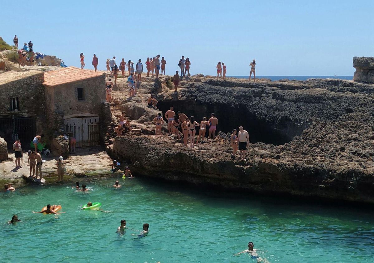 Neben den Fischerhäuschen der Cala S'Almunia stürzen sich Teilnehmer einer geführten Tour in ein Naturbecken.