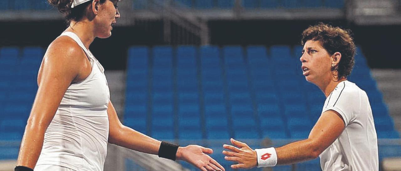 Garbiñe Muguruza se choca la mano con Carla Suárez, ayer, durante el partido de octavos de final del torneo olímpico de dobles en Tokio 2020. | | COE