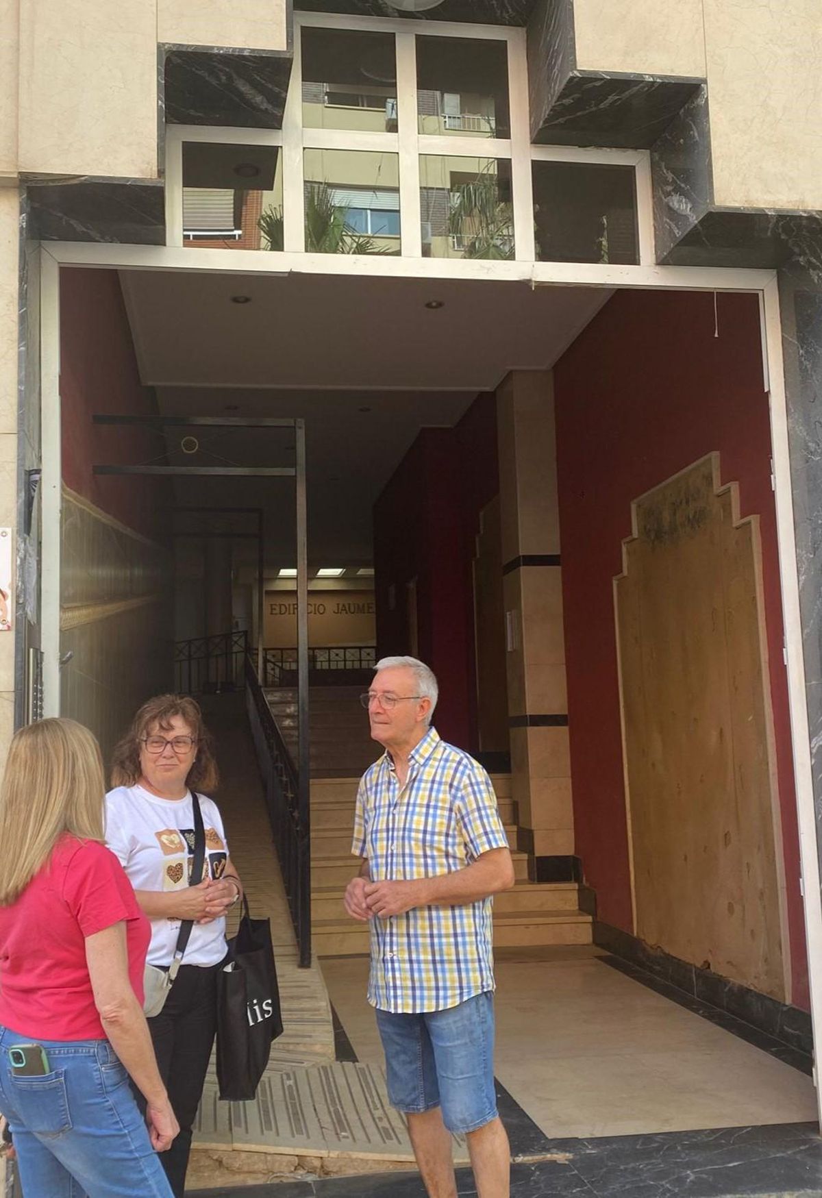 Un grupo de vecinos frente al portal del edificio sin puerta.