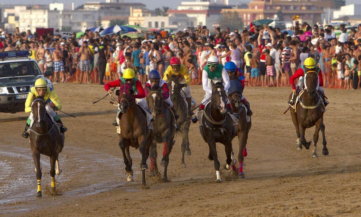 GRA209. SANLÚCAR DE BARRAMEDA (CÁDIZ), 02/08/2013.- Varios jinetes compiten hoy en una de las pruebas de la primera jornada de la 168 edición de las Carreras de Caballos en las playas de Sanlúcar de Barrameda (Cádiz), cuyo primer ciclo concluirá el próximo domingo. EFE/Román Ríos