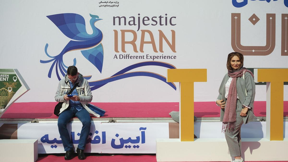 Una mujer posa frente al eslogan de la campaña turística oficial &quot;Majestuoso Irán. Una experiencia diferente&quot;, en la Exposición Internacional de Turismo de Teherán.