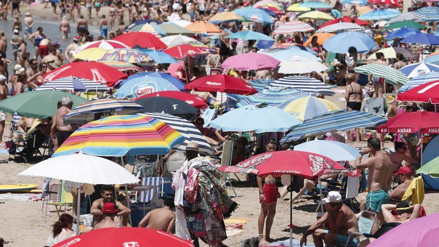 Miles de persona disfrutan de un día de playa.