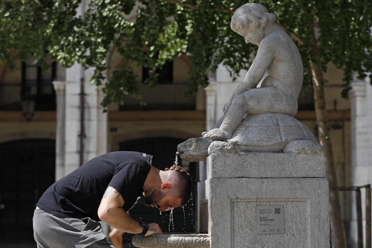 Un home es refresca a Girona en plena onada de calor aquest estiu.