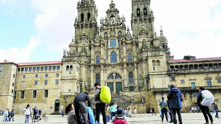 Peregrinos observando la Catedral de Santiago a su llegada al Obradoiro  / |  JESÚS PRIETO