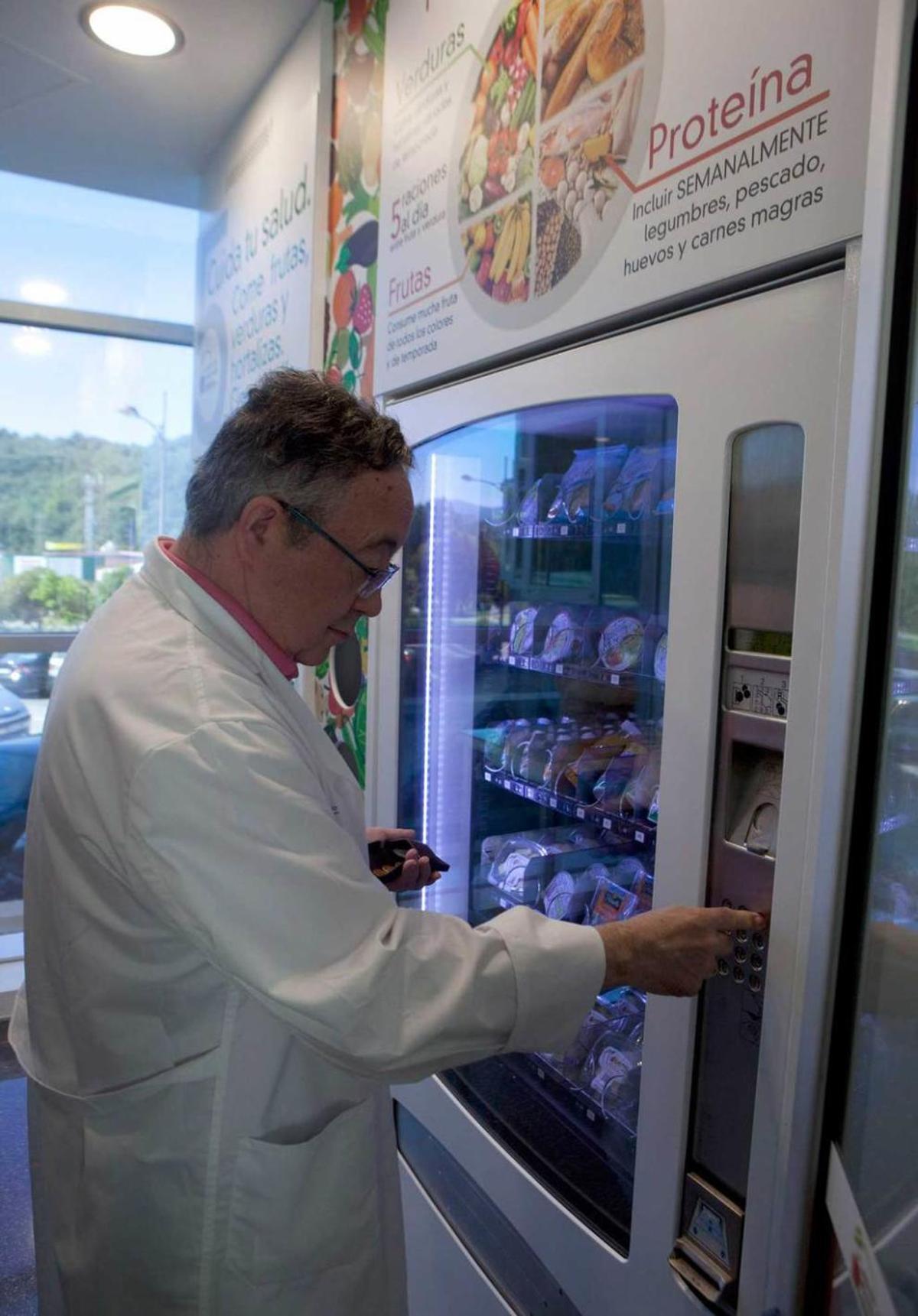 El director de Salud Pública del Nalón saca un producto de la máquina de vending en el espacio saludable.
