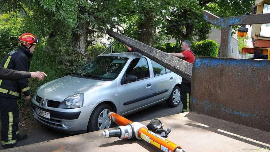 Los bomberos retiraron el poste de la luz caído sobre el Renault Clio, en Catasós. // Bernabé/Javier Lalín