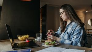 Una persona comiendo mientras teletrabaja.