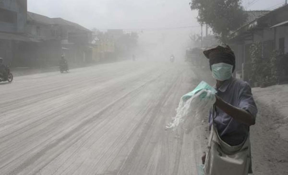 Un home ven mascaretes en un carrer cobert de cendra a Muntilan (Indonèsia). L’èxode continua als pobles pròxims al volcà Merapi, després que aquest registrés dimarts la seva erupció més explosiva.