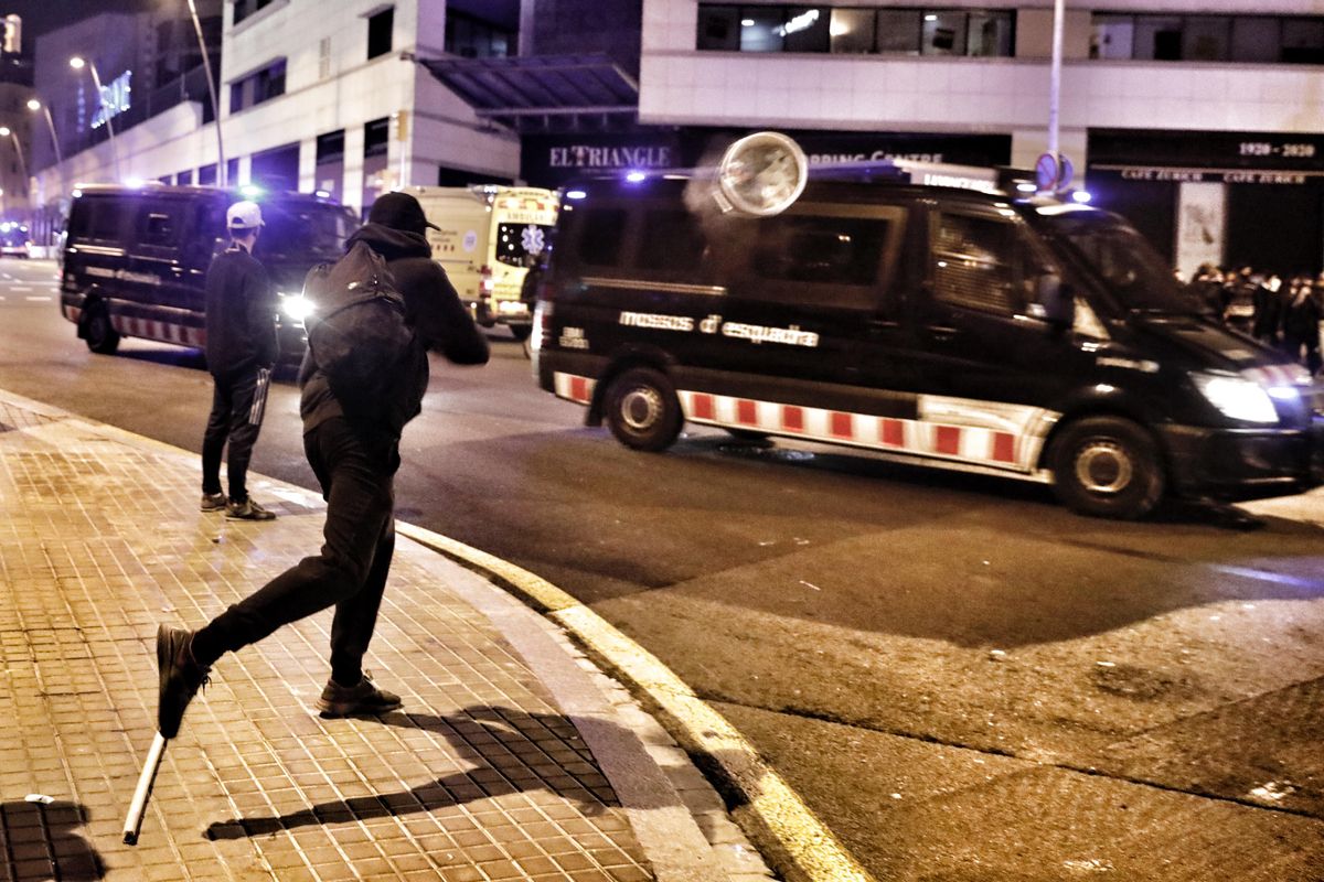 Un manifestante lanza un objeto del mobiliario urbano contra un furgón de los Mossos d’Esquadra, este viernes en Barcelona.