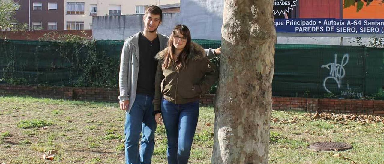 Tarik Vázquez y Alba López posan junto a un árbol del parque de la plaza de la iglesia de Lugones.