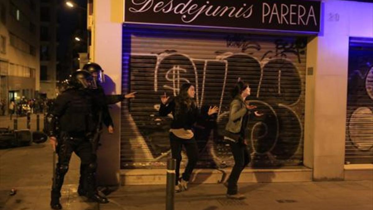 Dos mossos antidisturbios junto a dos jóvenes, ayer, en las protestas de Gràcia.