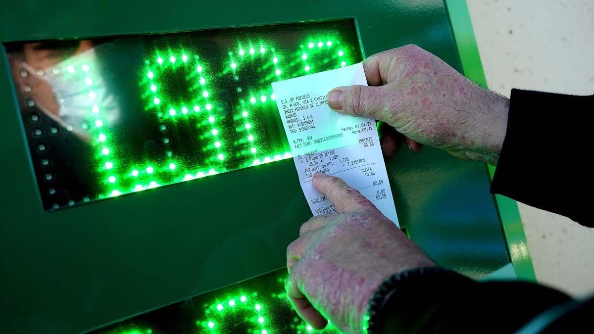 Un hombre comprueba el descuento de 20 céntimos en su ticket tras repostar en una gasolinera de Madrid.