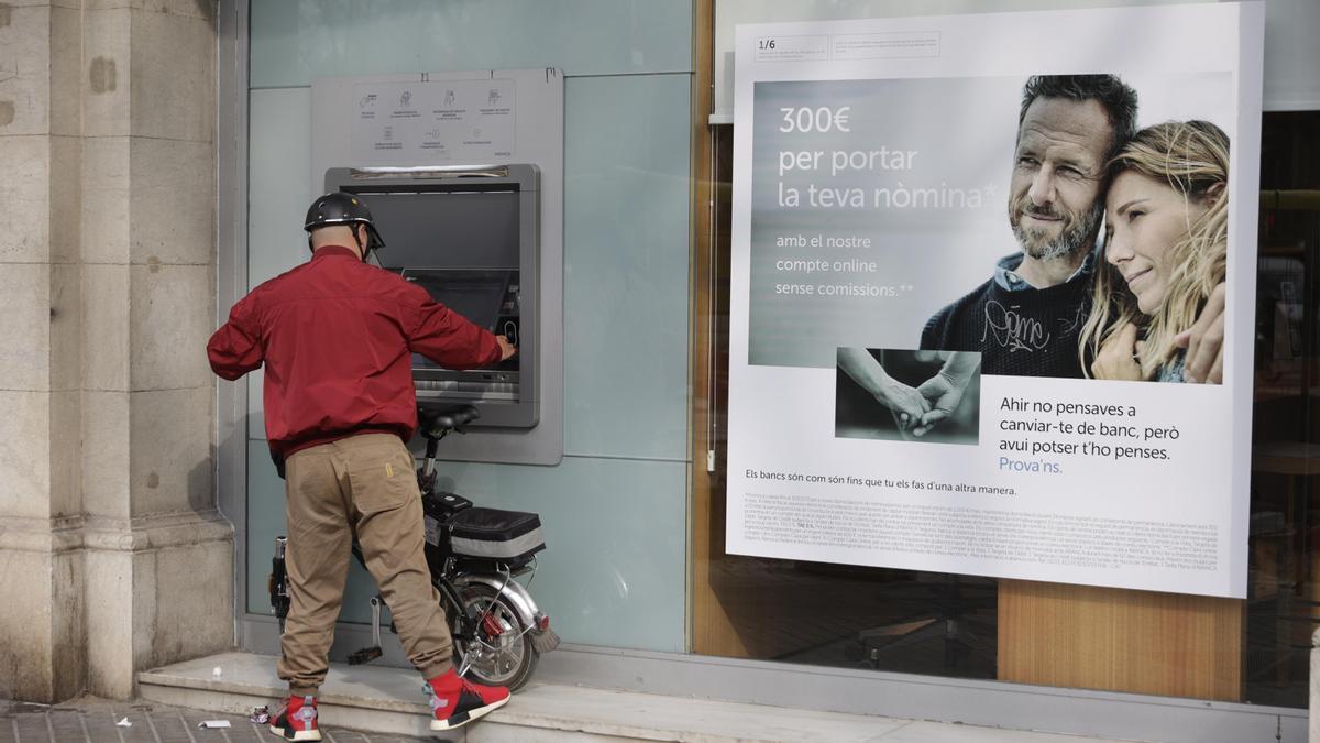 Un cliente saca efectivo del cajero automático de una entidad bancaria que publicita una cuenta remunerada ‘on line’.