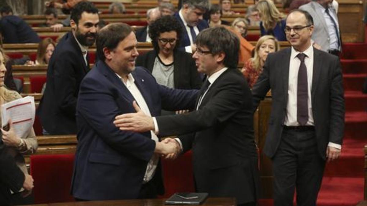 Junqueras y Puigdemont se saludan en el Parlament, en marzo.