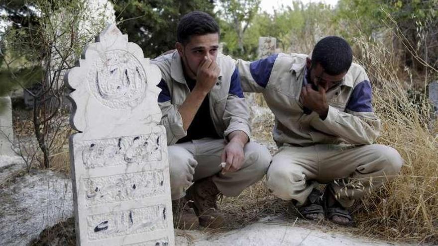 Miembros de la defensa civil siria lloran la muerte de un compañero.