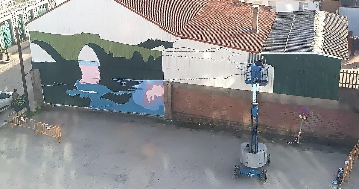 Fernando Yáñez, sobre la plataforma elevadora, perfilando su mural este domingo en Negreira