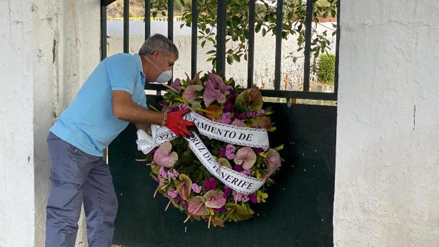 Un operario municipal coloca una corona de flores en la puerta de un cementerio chicharrero.