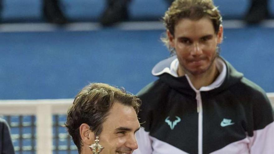 Federer sonríe con el trofeo ante Rafa Nadal. // Efe
