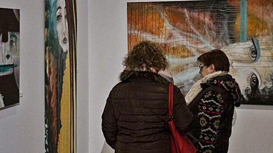 Dos mujeres contemplan las obras de Carmen Ratón.